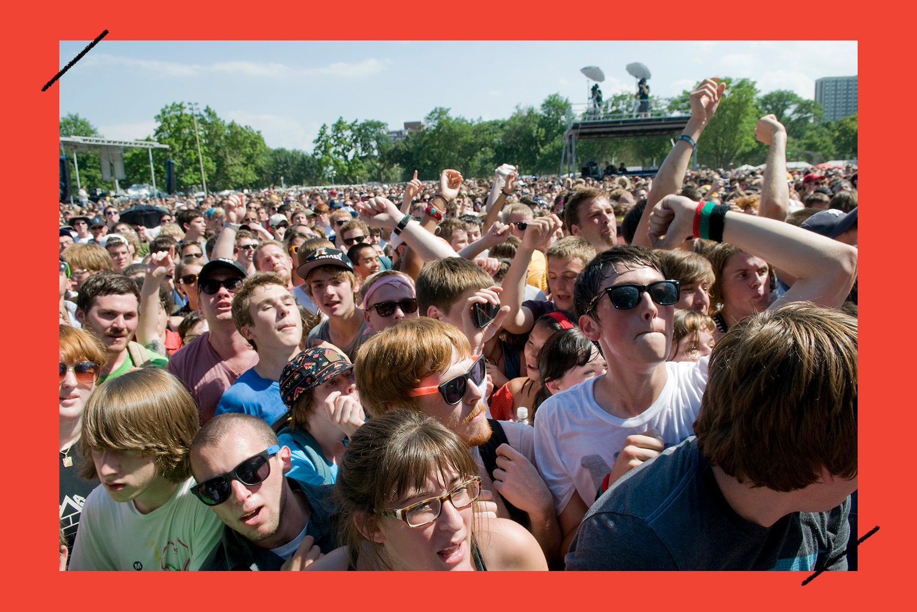 A crowd of people as seen from the stage at a sunny outdoor music festival.